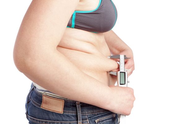 fat-woman-measuring-calipers-layer-fat-belly-white-wall
